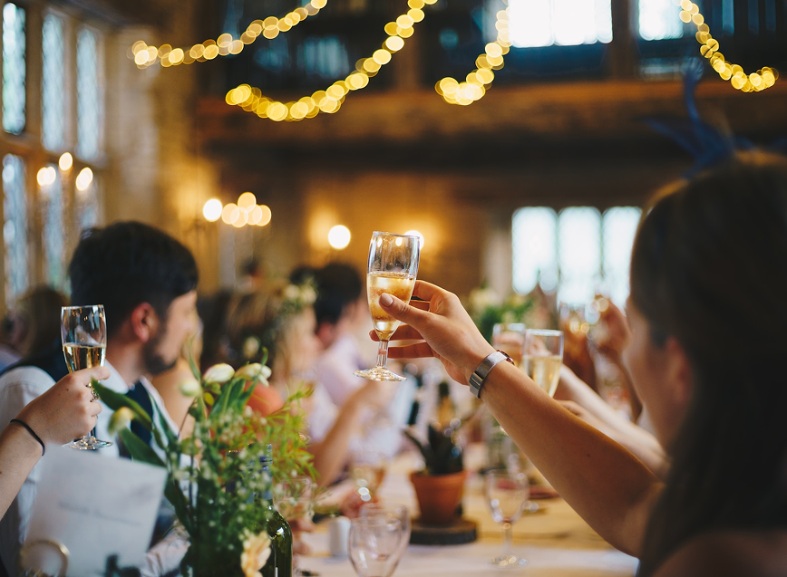 Guests raising glasses for a toast under string lights