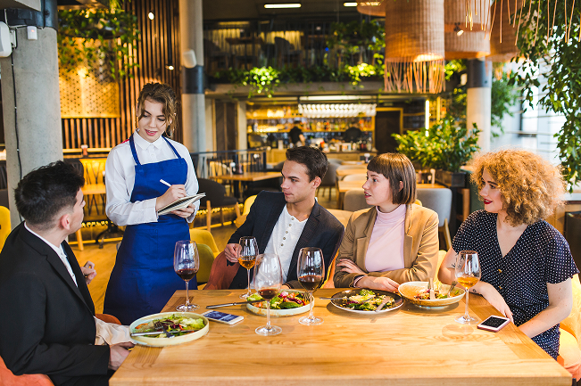 A waitress taking orders from happy guests at a table