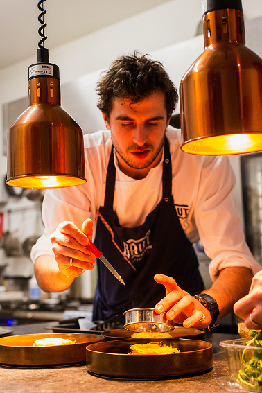 Chef Adam Joseph plating a dish under heat lamps